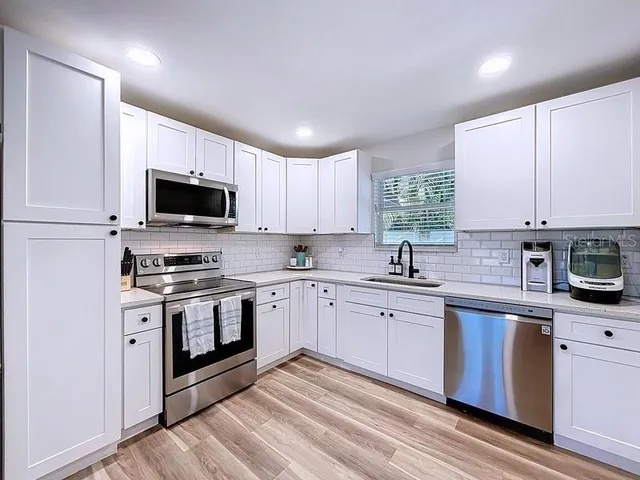 a kitchen with stainless steel appliances granite countertop a stove top oven a sink dishwasher a refrigerator and a microwave