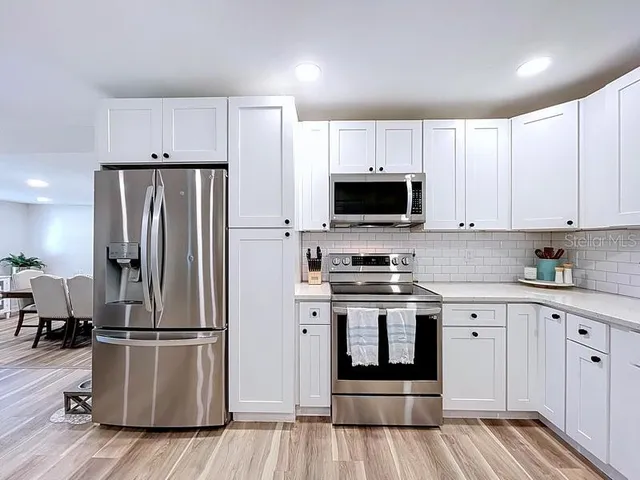 a kitchen with cabinets stainless steel appliances and wooden floor