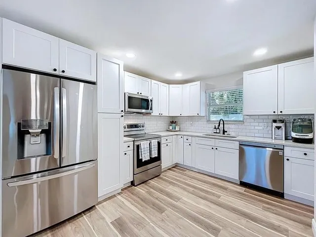 a kitchen with stainless steel appliances cabinets a sink and a center island