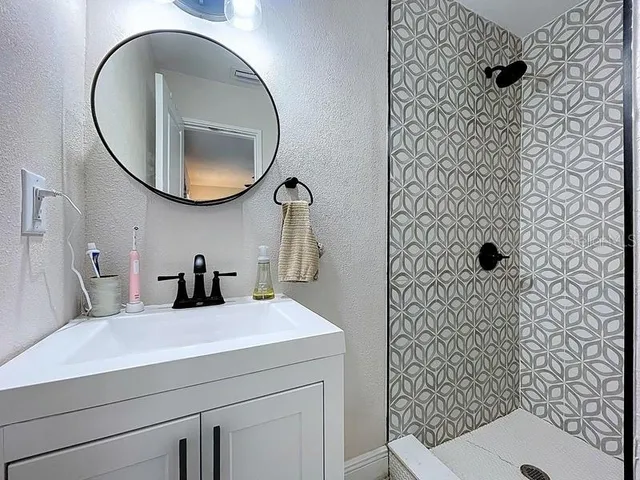 a bathroom with a sink a mirror a vanity and shower