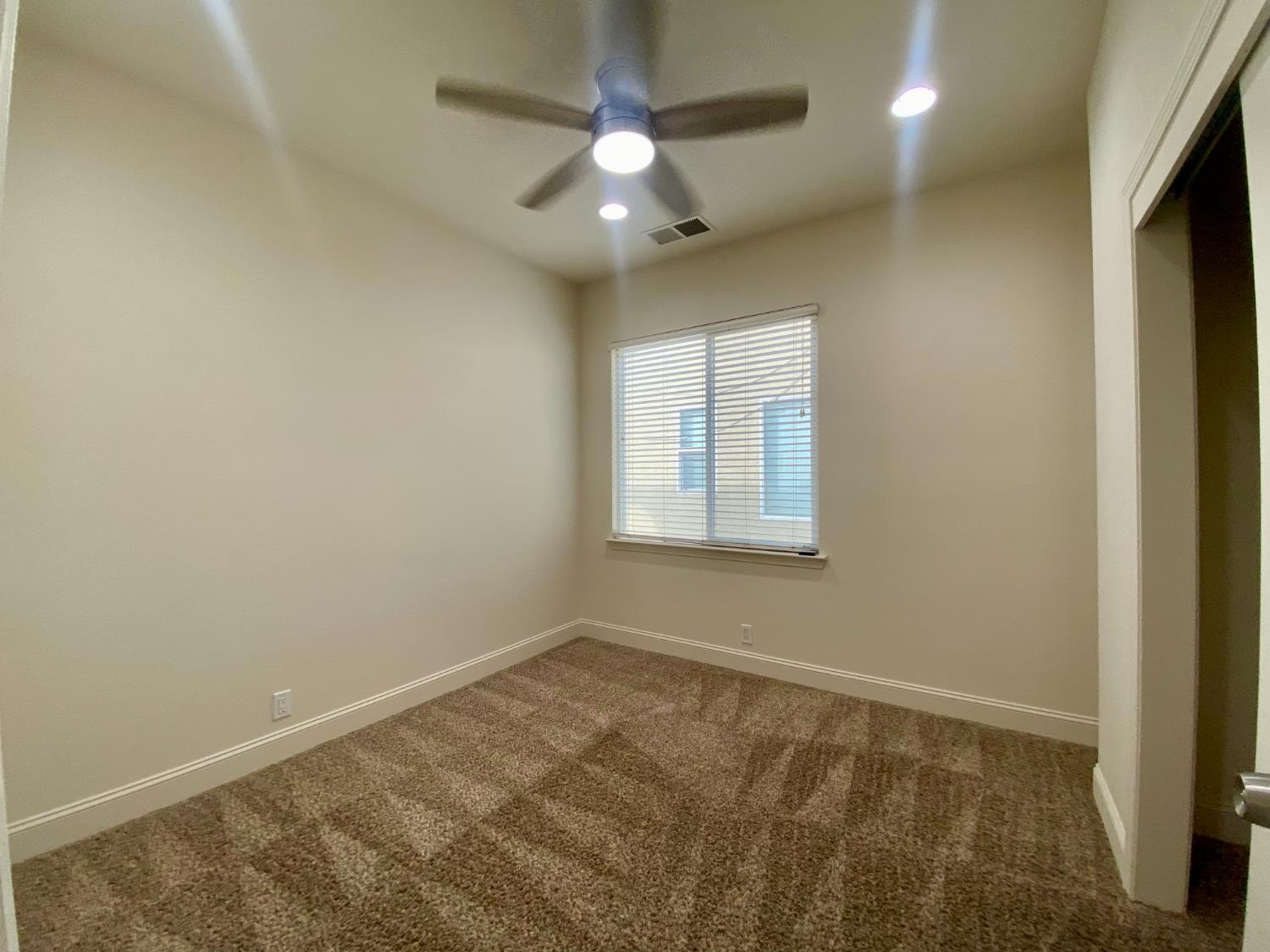 1227 CAVALAIRE Court Merced, CA 95348 - Photo 17 of 34 an empty room with a chandelier fan and windows
