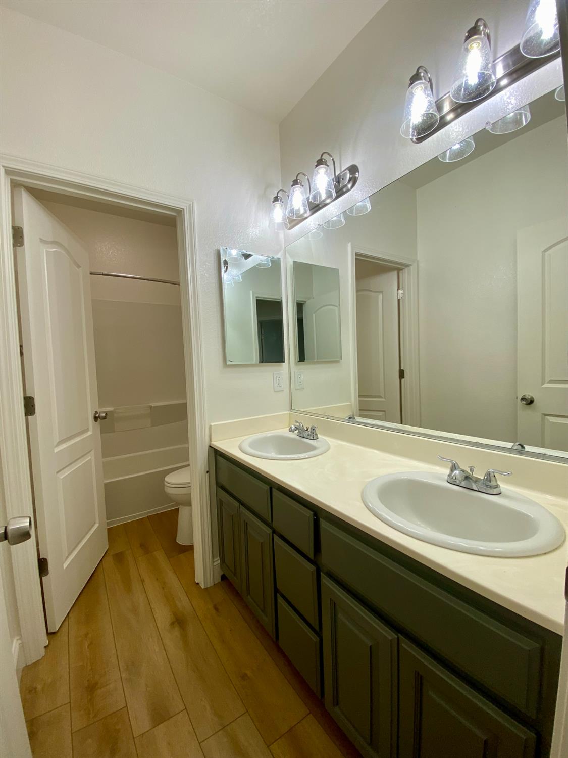 1227 CAVALAIRE Court Merced, CA 95348 - Photo 18 of 34 a bathroom with a double vanity sink a large mirror and a bathtub
