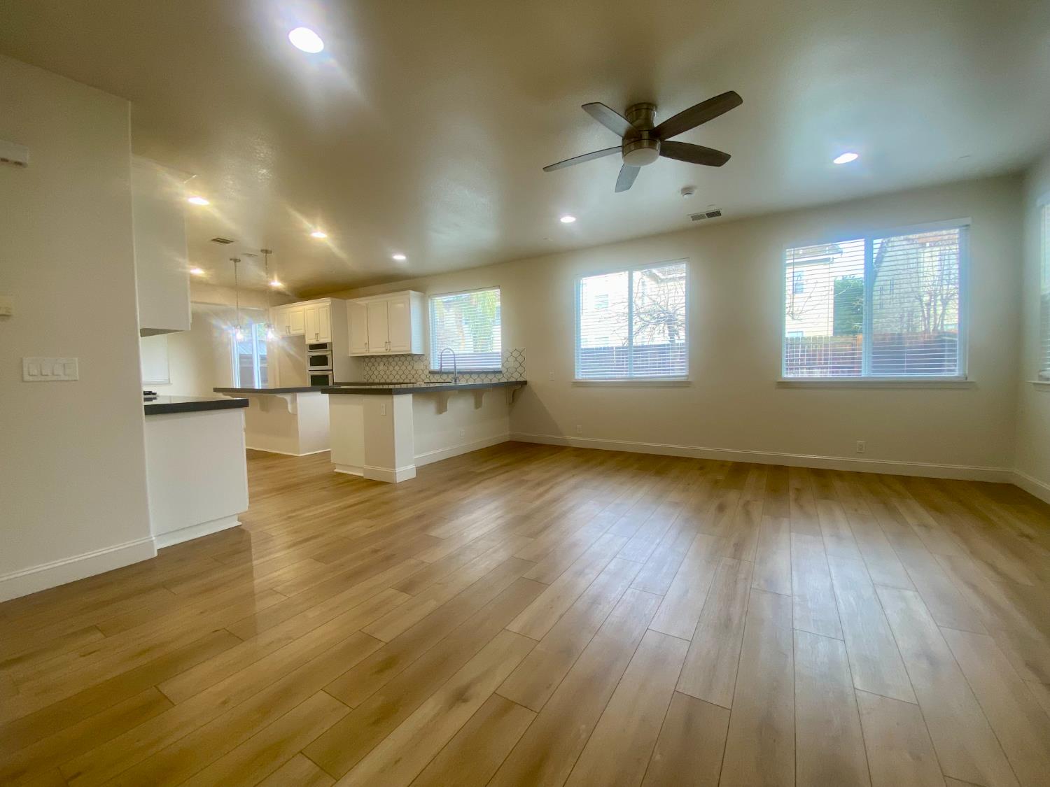 1227 CAVALAIRE Court Merced, CA 95348 - Photo 10 of 34 an empty room with wooden floor and a kitchen