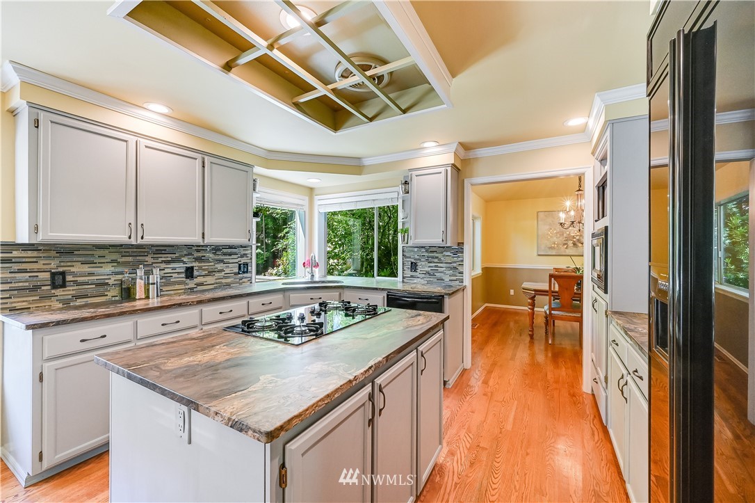 2716 187th Street Southeast Bothell, WA 98012 - Photo 8 of 37 a kitchen with a stove a sink a dining table and chairs with wooden floor