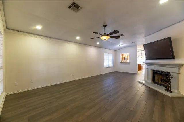 an empty room with wooden floor fireplace and windows