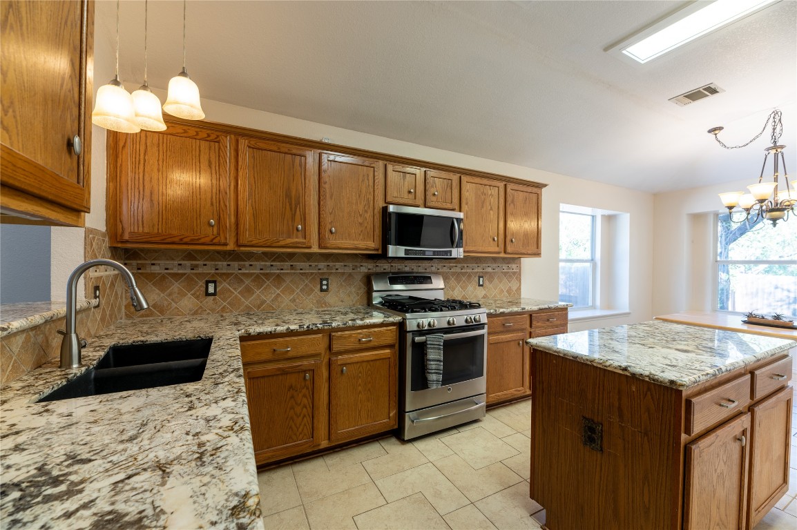 2604 Hutton Lane Leander, TX 78641 - Photo 9 of 27 a kitchen with granite countertop a sink stove and cabinets
