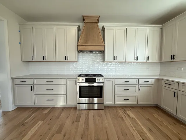 a kitchen with stainless steel appliances granite countertop a stove and a white cabinets