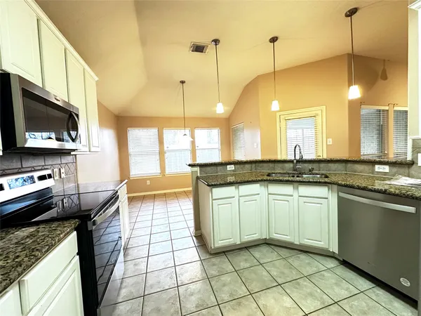 a kitchen with stainless steel appliances granite countertop a sink a stove top oven a counter space and cabinets