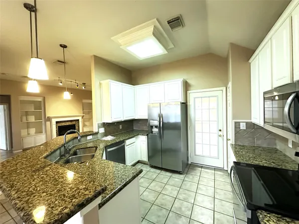 a kitchen with stainless steel appliances granite countertop a sink refrigerator and cabinets
