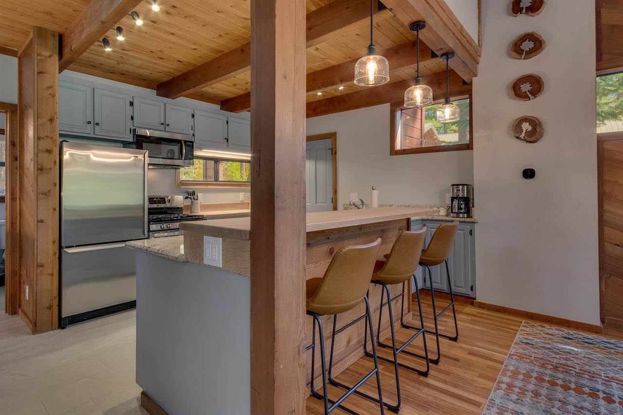 117 Basque Drive Truckee, CA 96161 - Photo 7 of 20 a kitchen with stainless steel appliances a refrigerator a sink a stove and chairs with wooden floor