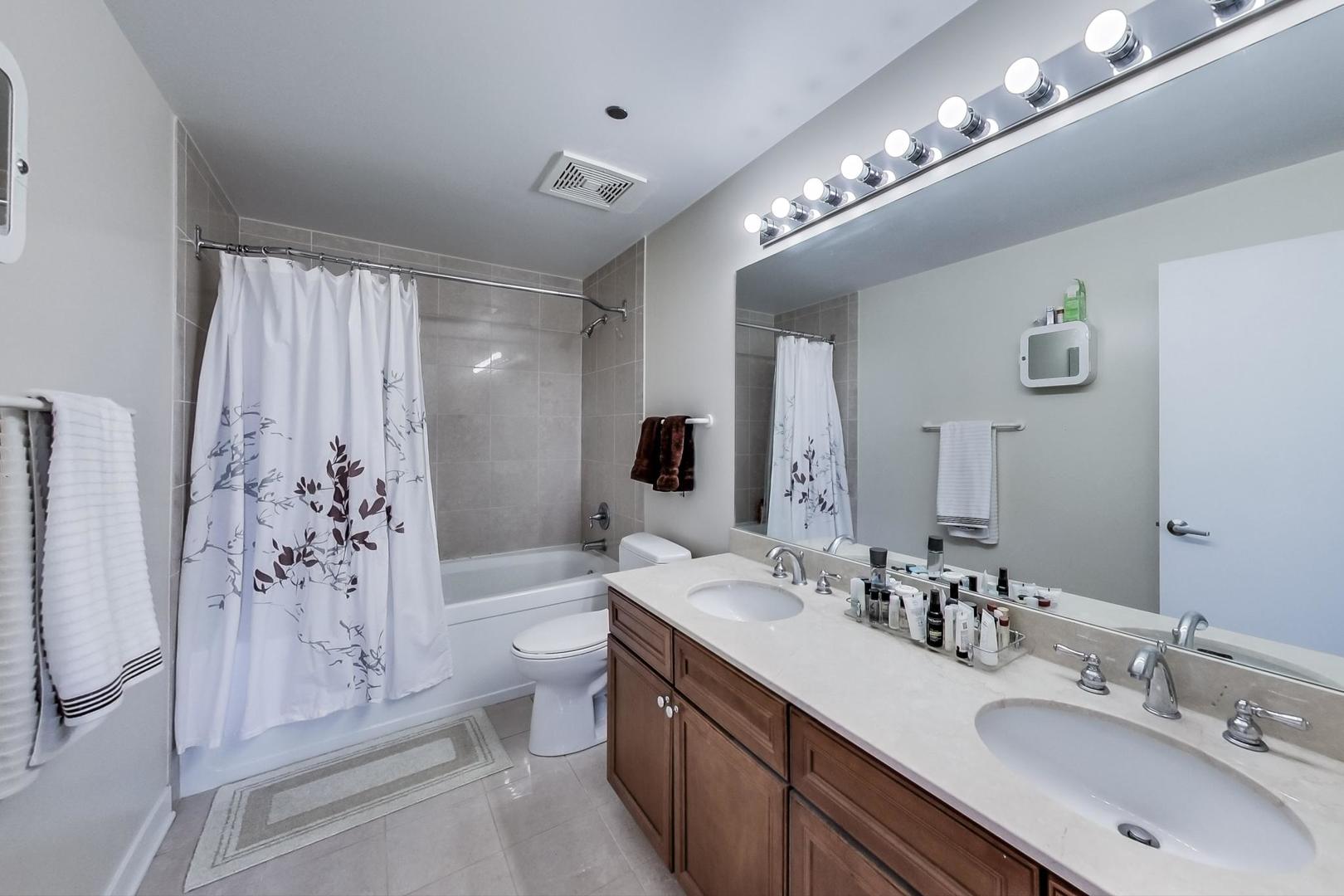 811 West 15th Place, Unit 606 Chicago, IL 60608 - Photo 13 of 22 a spacious bathroom with a double vanity sink a toilet a shower and a mirror