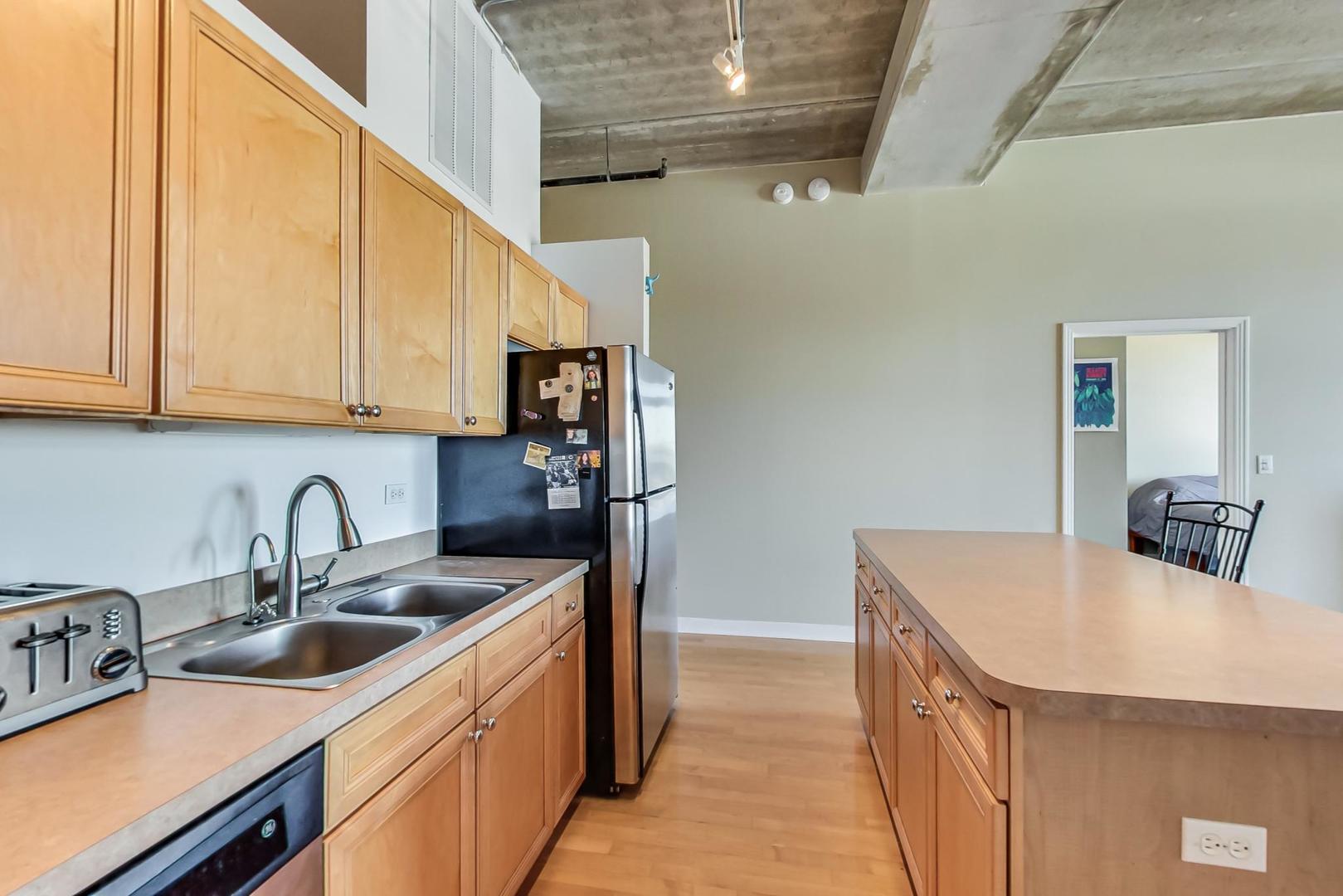 811 West 15th Place, Unit 606 Chicago, IL 60608 - Photo 7 of 22 a kitchen with stainless steel appliances granite countertop a sink a stove and a refrigerator with wooden cabinets