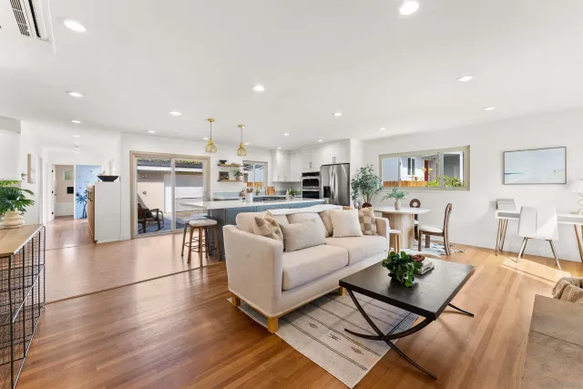 a living room with furniture and kitchen view with wooden floor