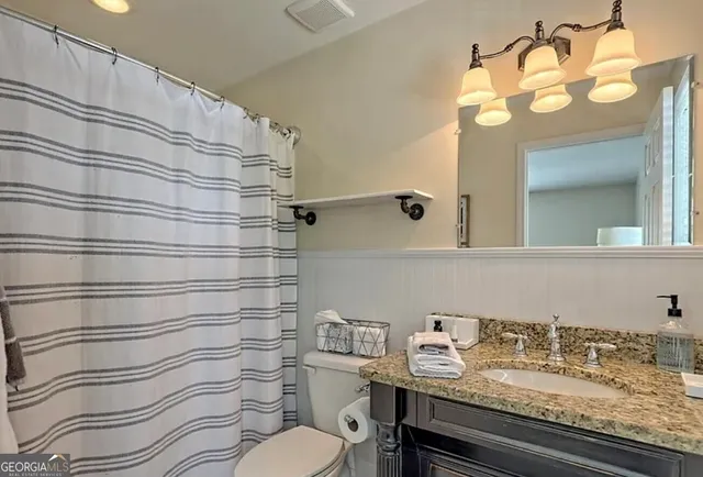 a bathroom with a granite countertop sink vanity mirror and toilet