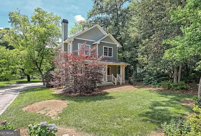 a front view of a house with a garden and trees