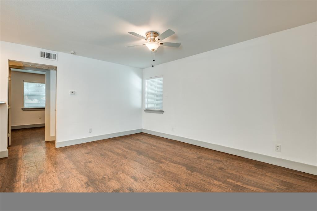 4633 Fairmount Street, Unit 109 Dallas, TX 75219 - Photo 5 of 14 Spacious room featuring wood-finish flooring, white walls, and a ceiling fan with integrated lighting