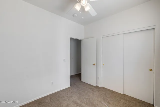 a view of an empty room with a chandelier fan