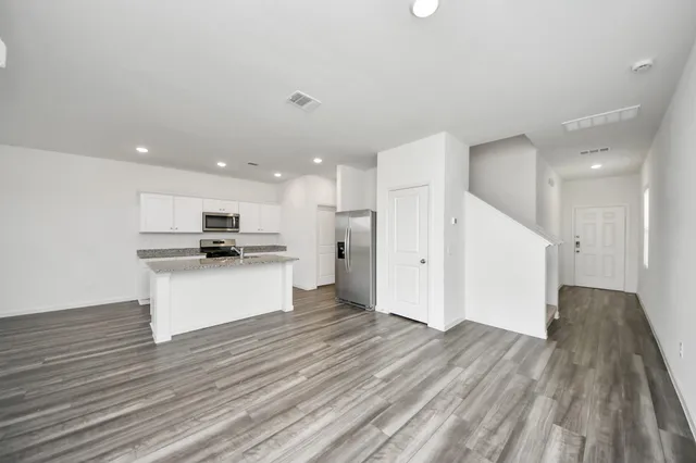 a view of kitchen with kitchen island granite countertop a stove top oven a sink and a refrigerator