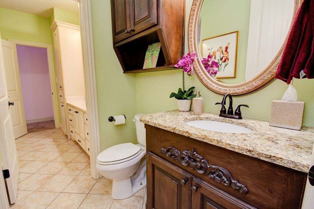 6506 15th Drive Lubbock, TX 79416 - Photo 31 of 42 a bathroom with a granite countertop toilet sink and mirror