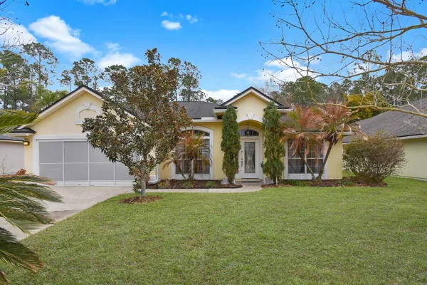 a view of a house with a big yard and large tree