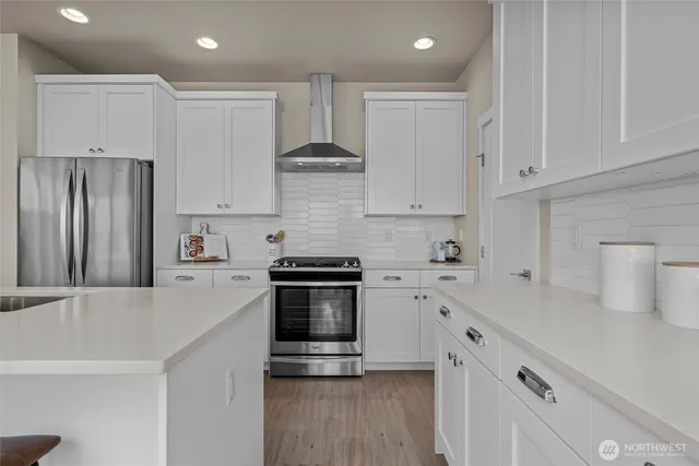 a kitchen with stainless steel appliances a refrigerator a sink a stove and white cabinets