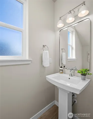 a view of a hallway with wooden floor and a bathroom
