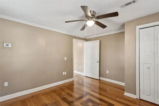 an empty room with wooden floor fan and windows