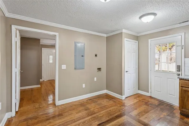 a view of an empty room and bathroom with wooden floor