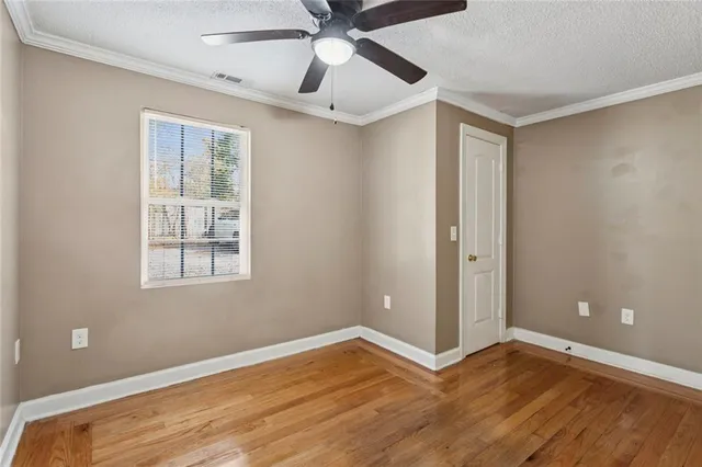a view of an empty room with window and wooden floor
