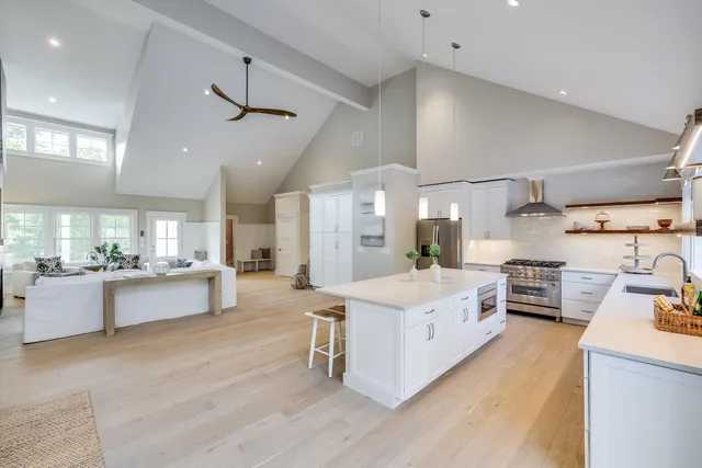 a large kitchen with stainless steel appliances a stove a sink dishwasher and a dining table with wooden floor