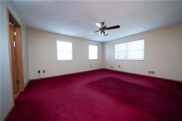 an empty room with windows and ceiling fan