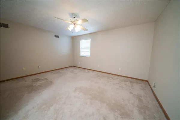 an empty room with windows and chandelier fan