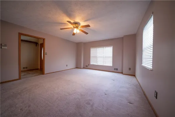 an empty room with windows and fan