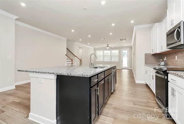 a large kitchen with stainless steel appliances a large counter top a stove a refrigerator and a cabinets