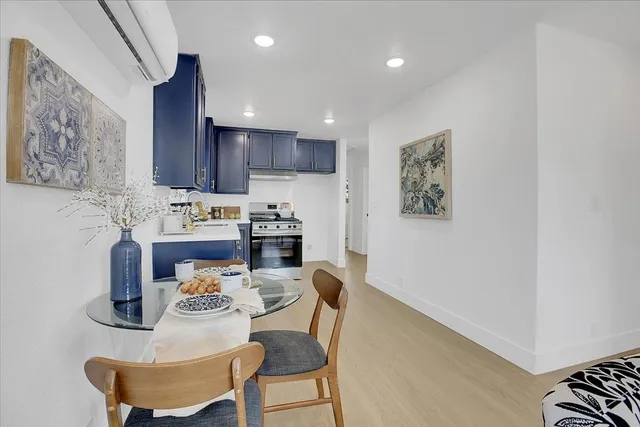 a kitchen with a refrigerator a stove a sink and a dining table with wooden floor