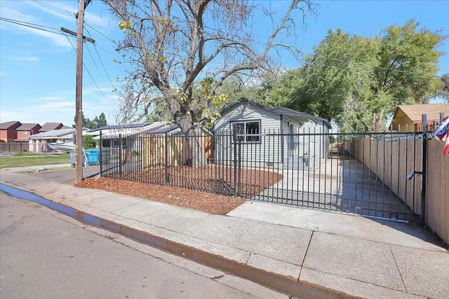 a view of backyard with large trees and wooden fence