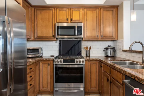 a kitchen with granite countertop a sink stove and refrigerator