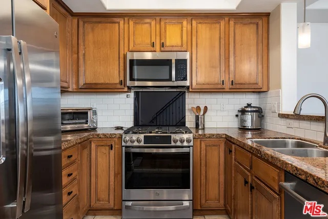 a kitchen with granite countertop a sink stove and refrigerator