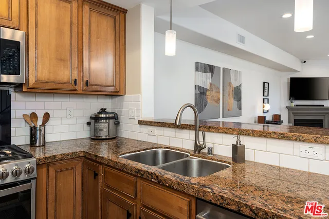 a kitchen with granite countertop a sink a counter top space cabinets and stainless steel appliances