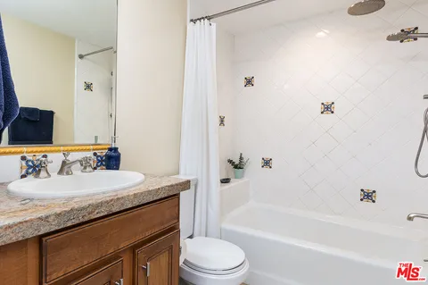 a bathroom with a granite countertop sink toilet mirror and bathtub