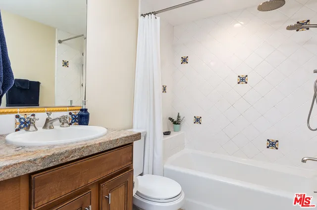 a bathroom with a granite countertop sink toilet mirror and bathtub