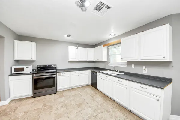 a large kitchen with granite countertop a refrigerator and a sink
