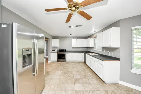 a kitchen with a refrigerator and white cabinets