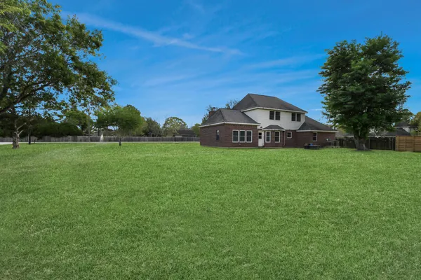 a view of a house with a big yard and large trees
