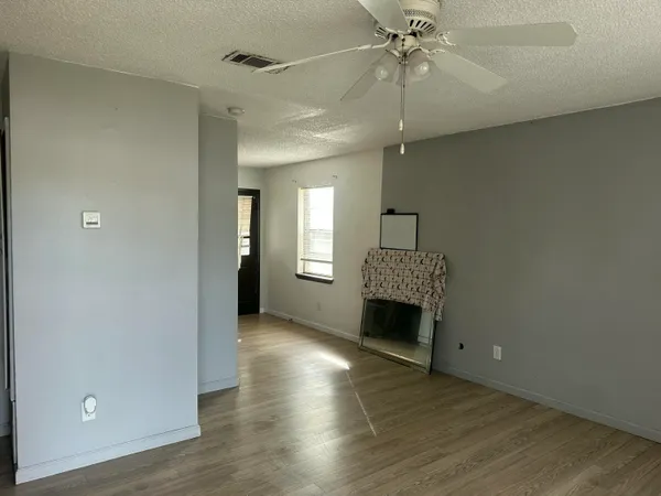 an empty room with wooden floor fireplace and windows