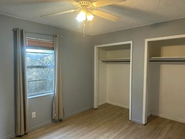 an empty room with wooden floor closet and windows