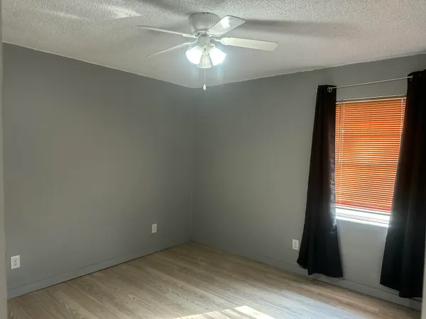 an empty room with windows and fan