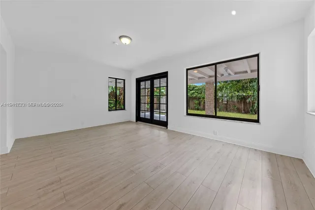 a view of an empty room with a window and wooden floor