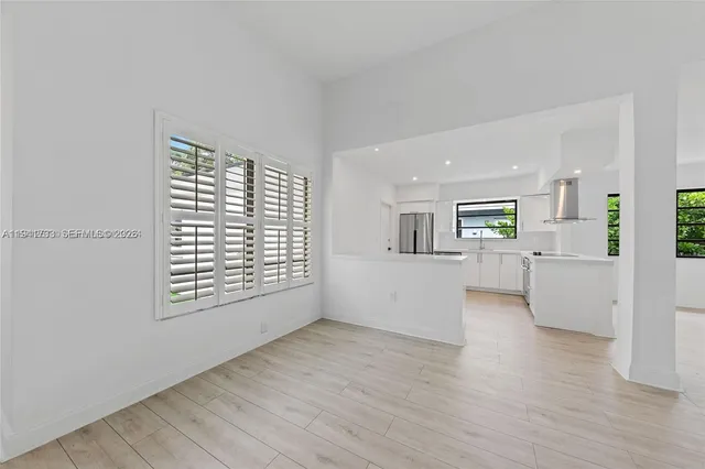a view of a kitchen and an empty room with wooden floor and a kitchen