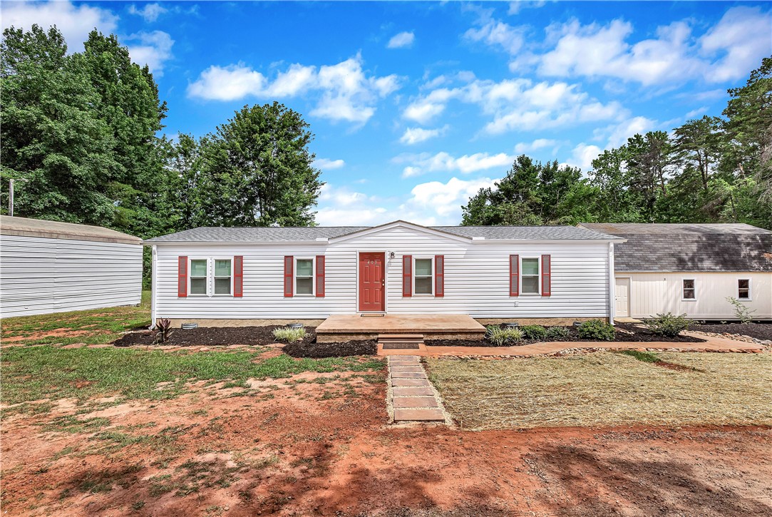 403 Hancox Place Westminster, SC 29693 - Photo 4 of 39 A quaint residence featuring white siding and red shutters, nestled amidst verdant trees.